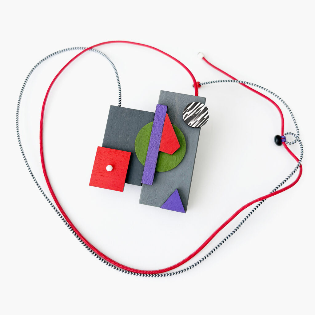 Geometric wooden necklace with red and black-and-white cords and sliding bead adjustment