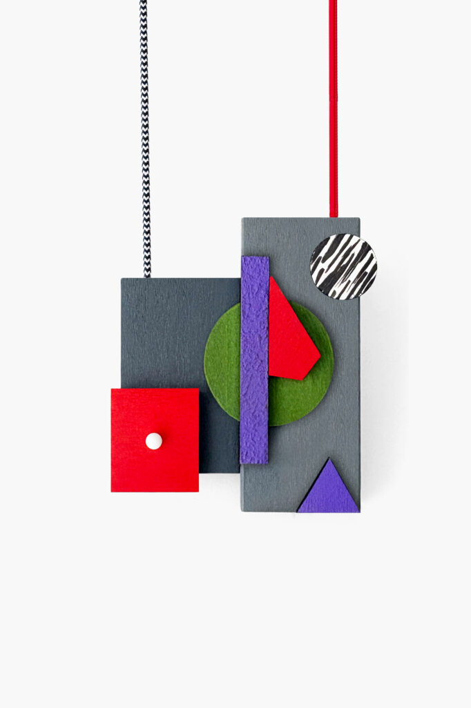 Red, purple and green geometric wooden necklace shown vertically on a white background