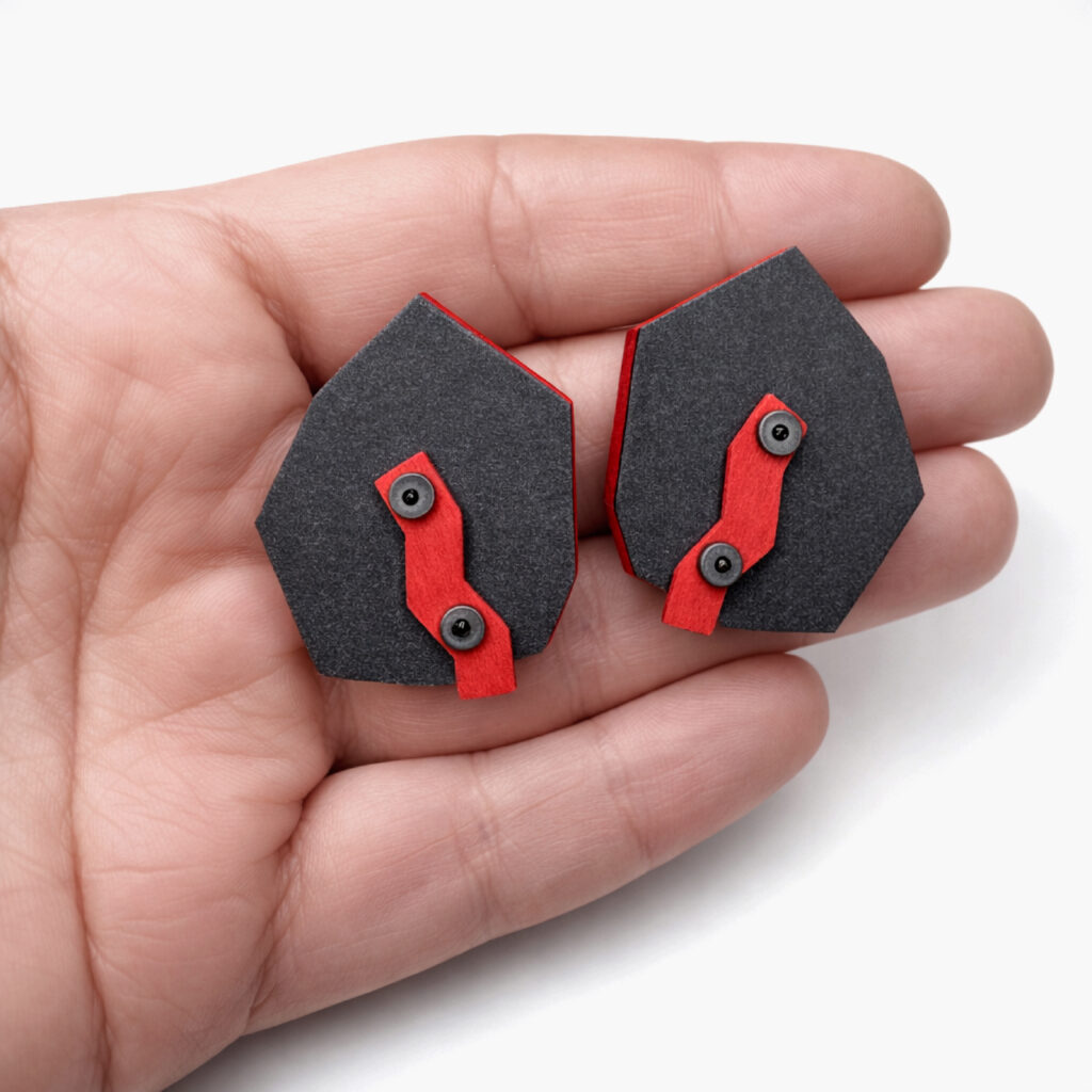Black red industrial wooden earrings shown in hand for scale
