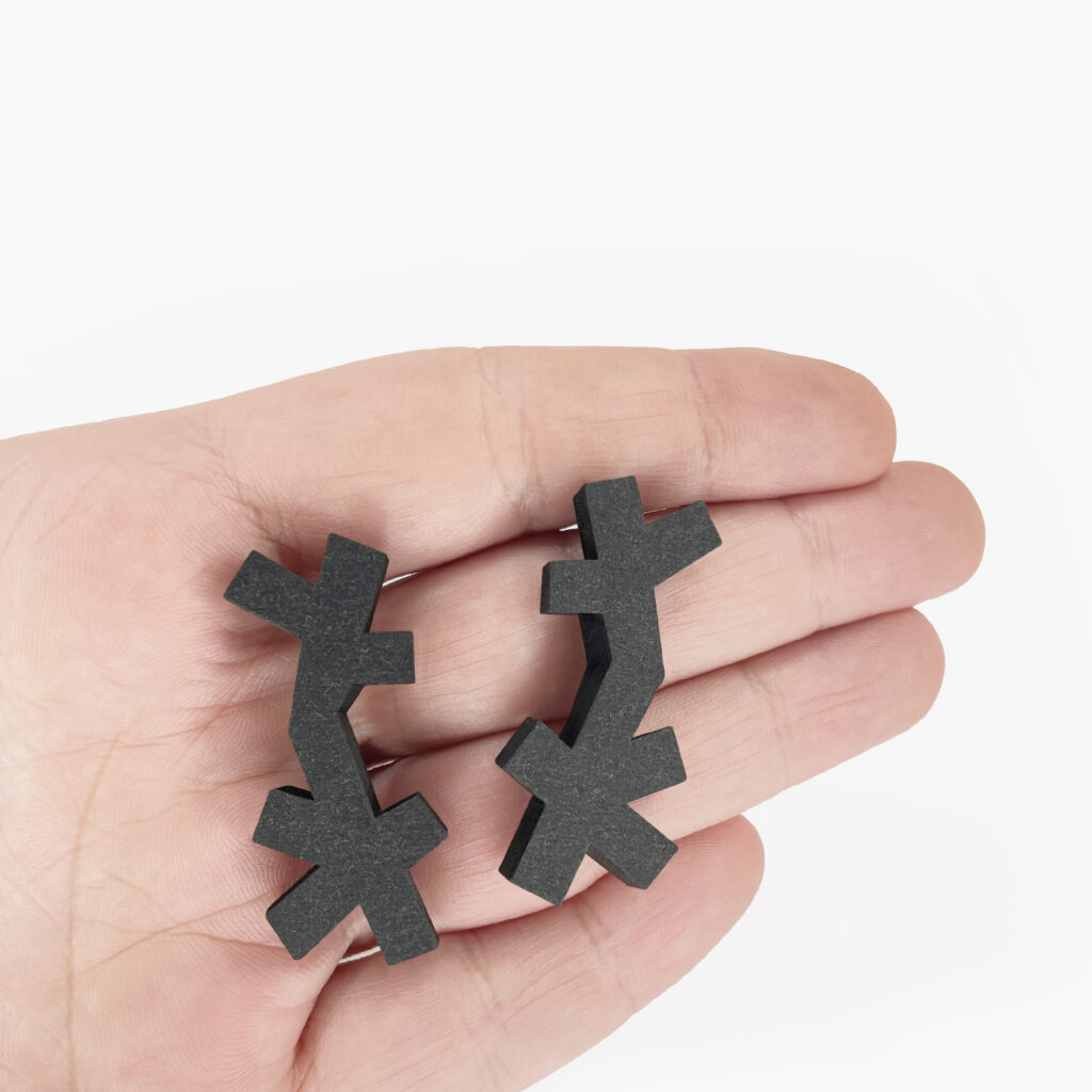Black abstract wooden earrings shown in hand to demonstrate size and proportions