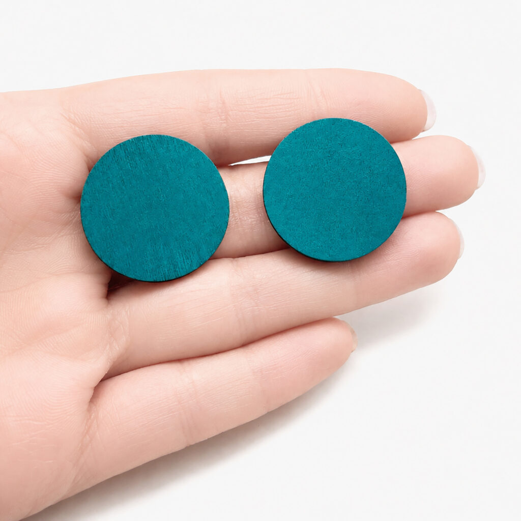 Petrol wooden disc stud earrings shown in hand
