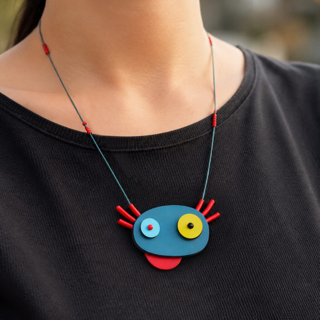 Colorful abstract axolotl statement necklace worn with a black top
