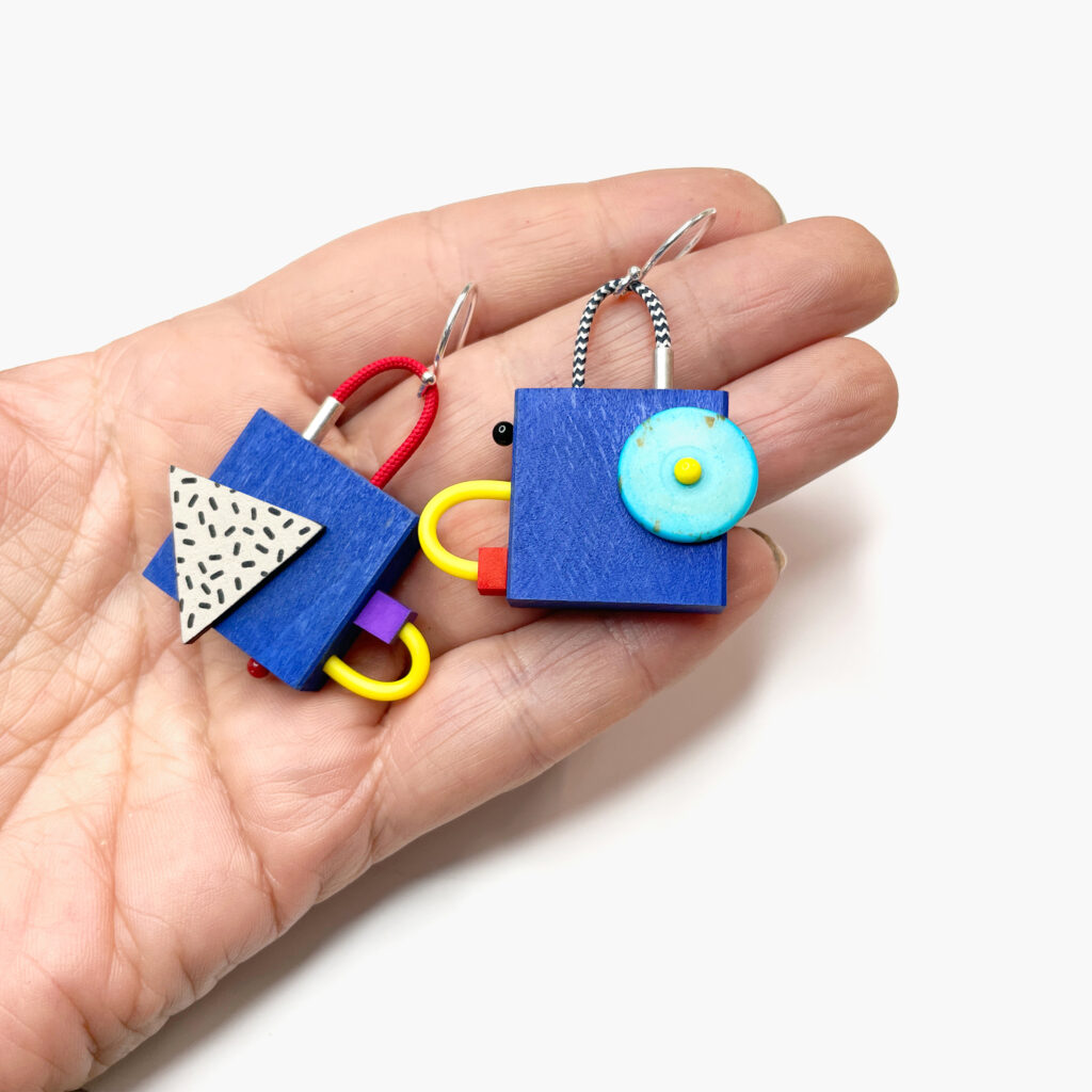 Colorful geometric dangle earrings with hand-painted wooden shapes shown in hand