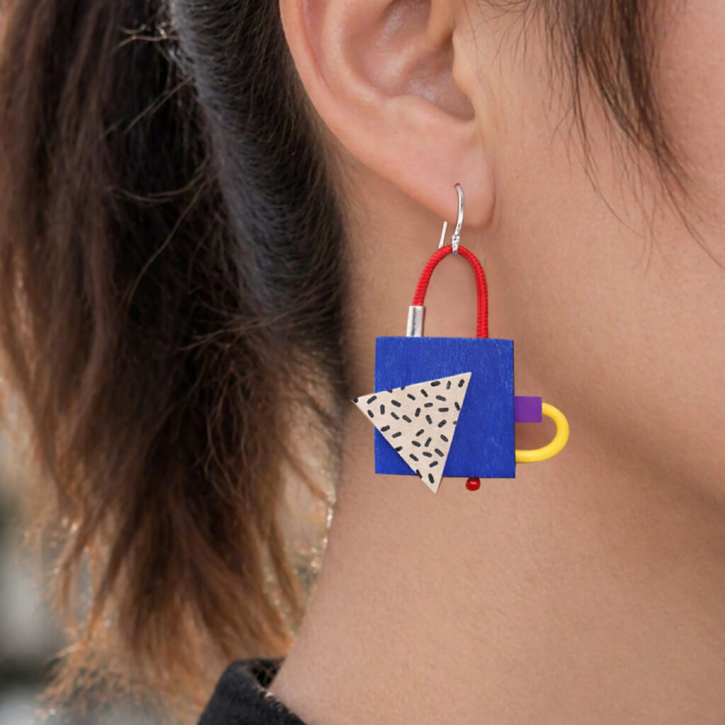 Colorful geometric statement earring with black-and-white triangular detail worn on ear