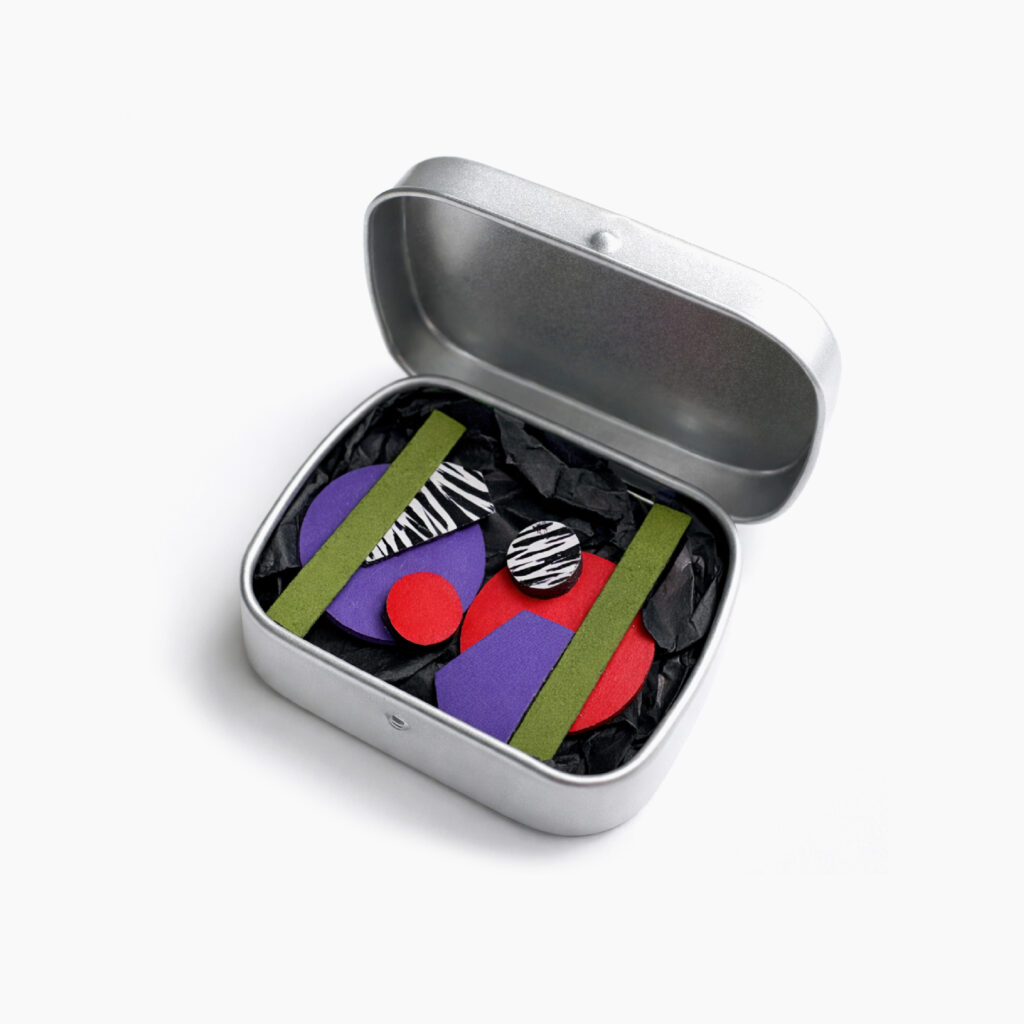 Colorful mismatched statement wooden earrings presented in a metal gift box