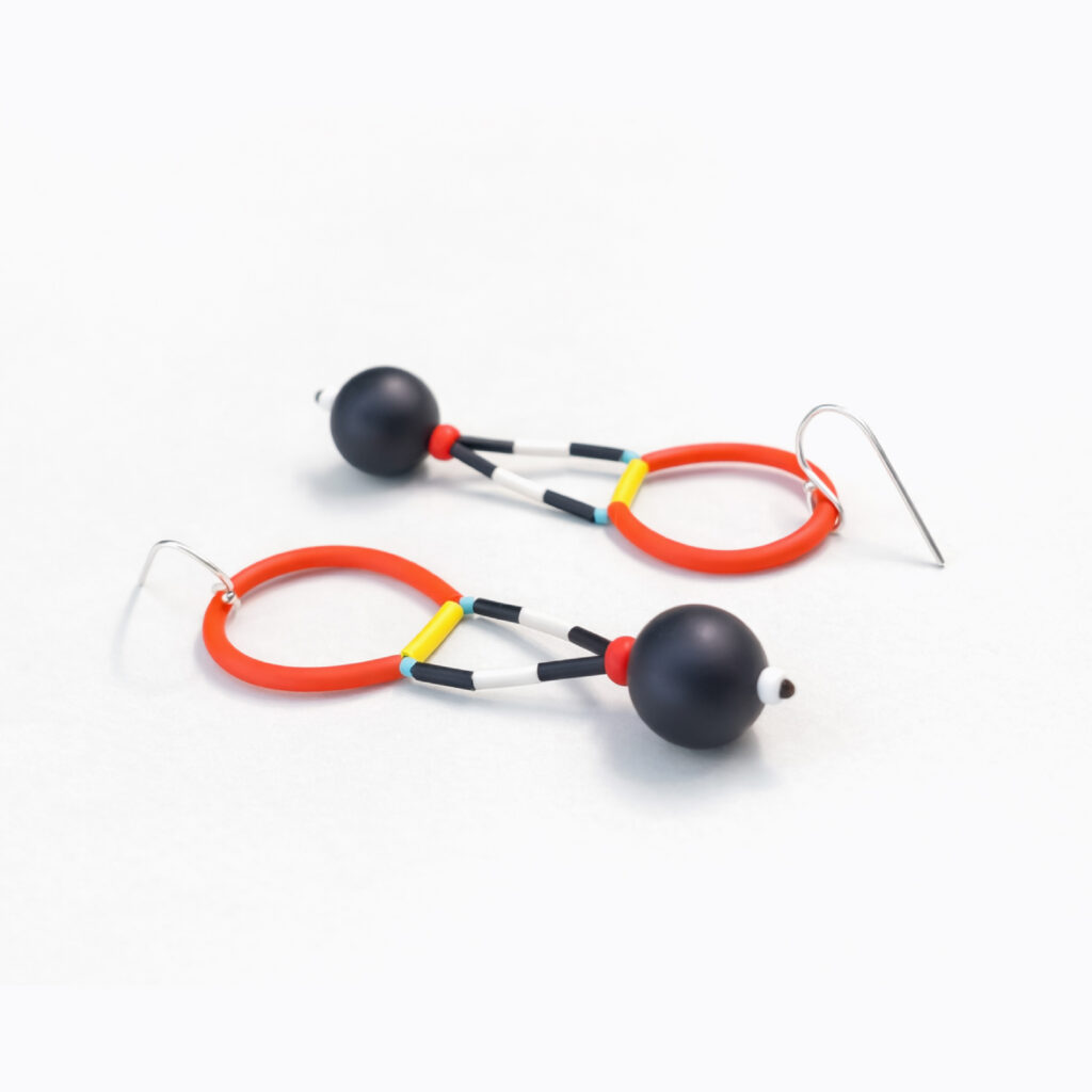 Red and black wooden dangle earrings with circular frames and black beads – angled view