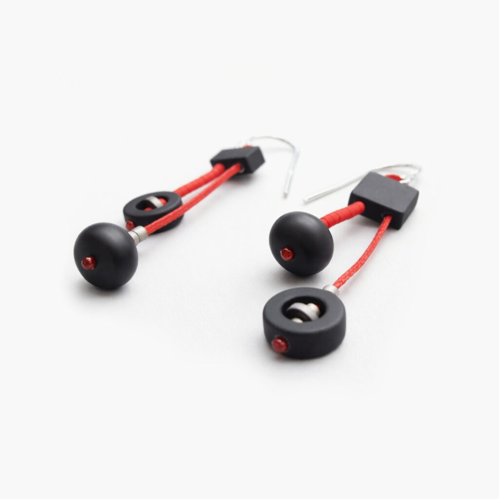 Black and red handmade geometric earrings with matte black beads – angled view