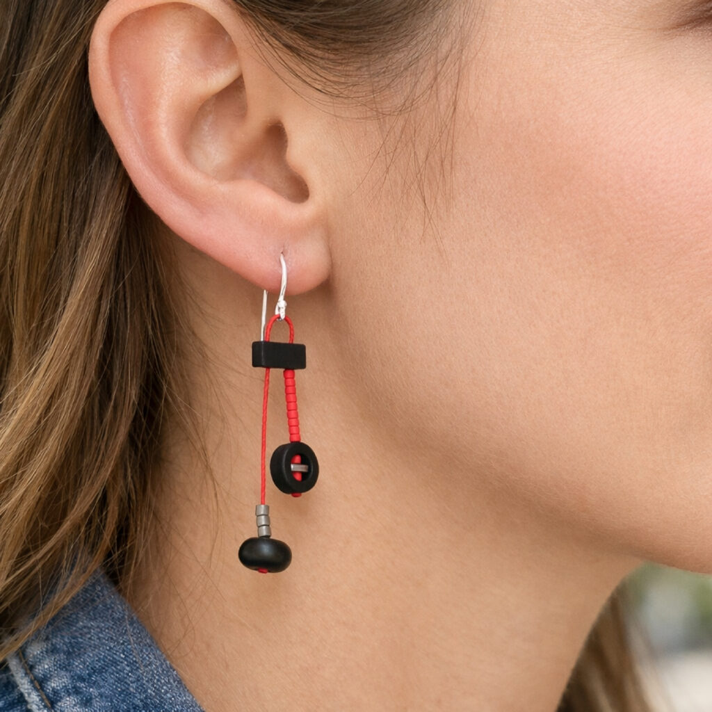 1. ong black and red geometric dangle earring worn on ear – close-up