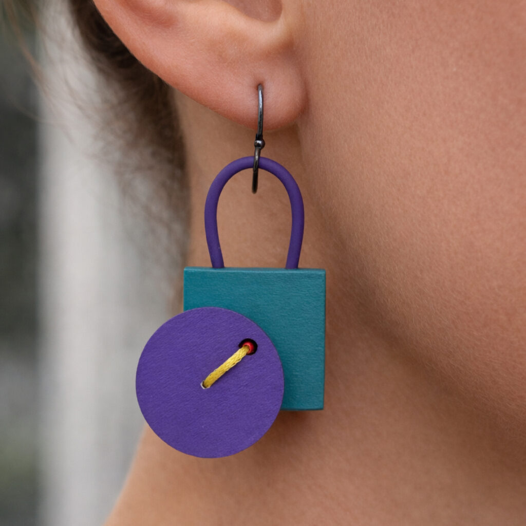 Purple and turquoise geometric statement earring worn on ear