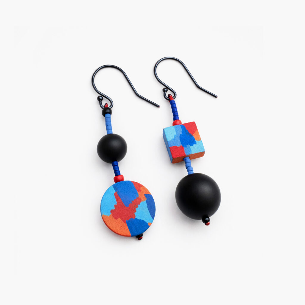 Pair of mismatched geometric dangle earrings with red and blue patterns on white background