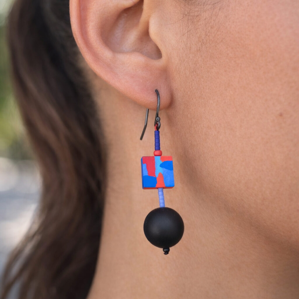 Colorful mismatched wooden earrings displayed in a metal gift box