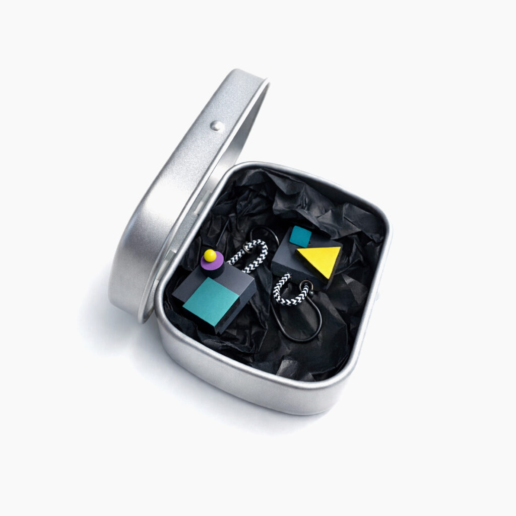Colorful mismatched earrings presented in a metal gift box