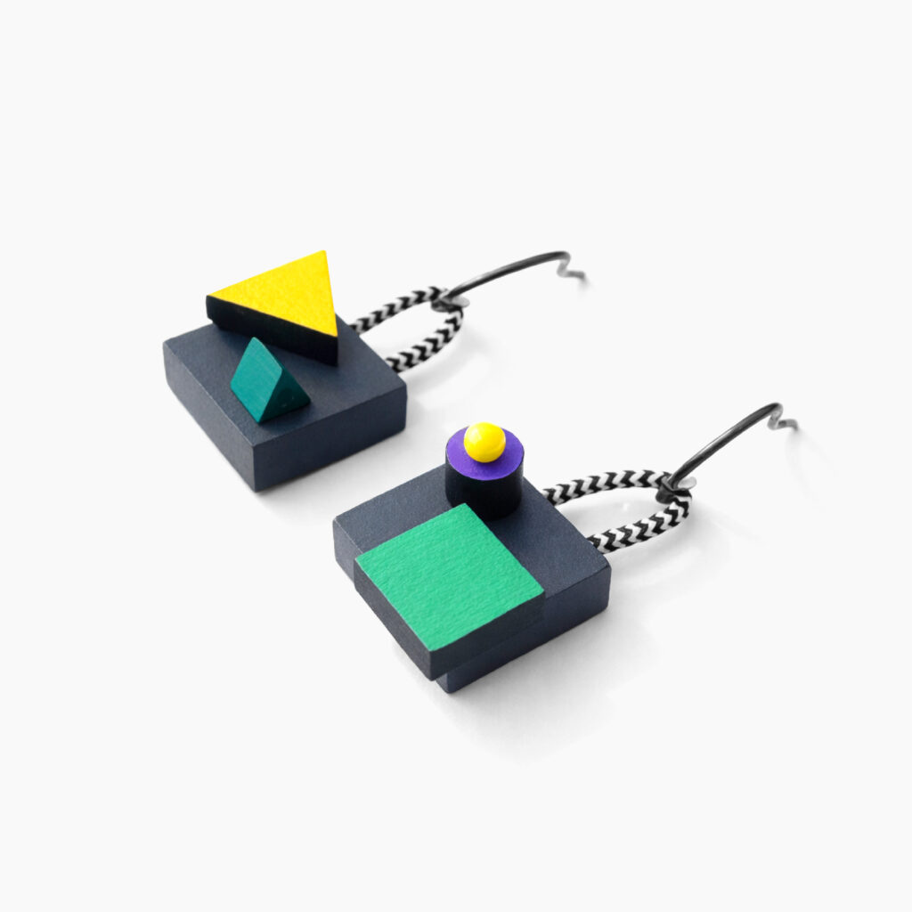 Angled view of colorful mismatched geometric wooden earrings showing their layered construction