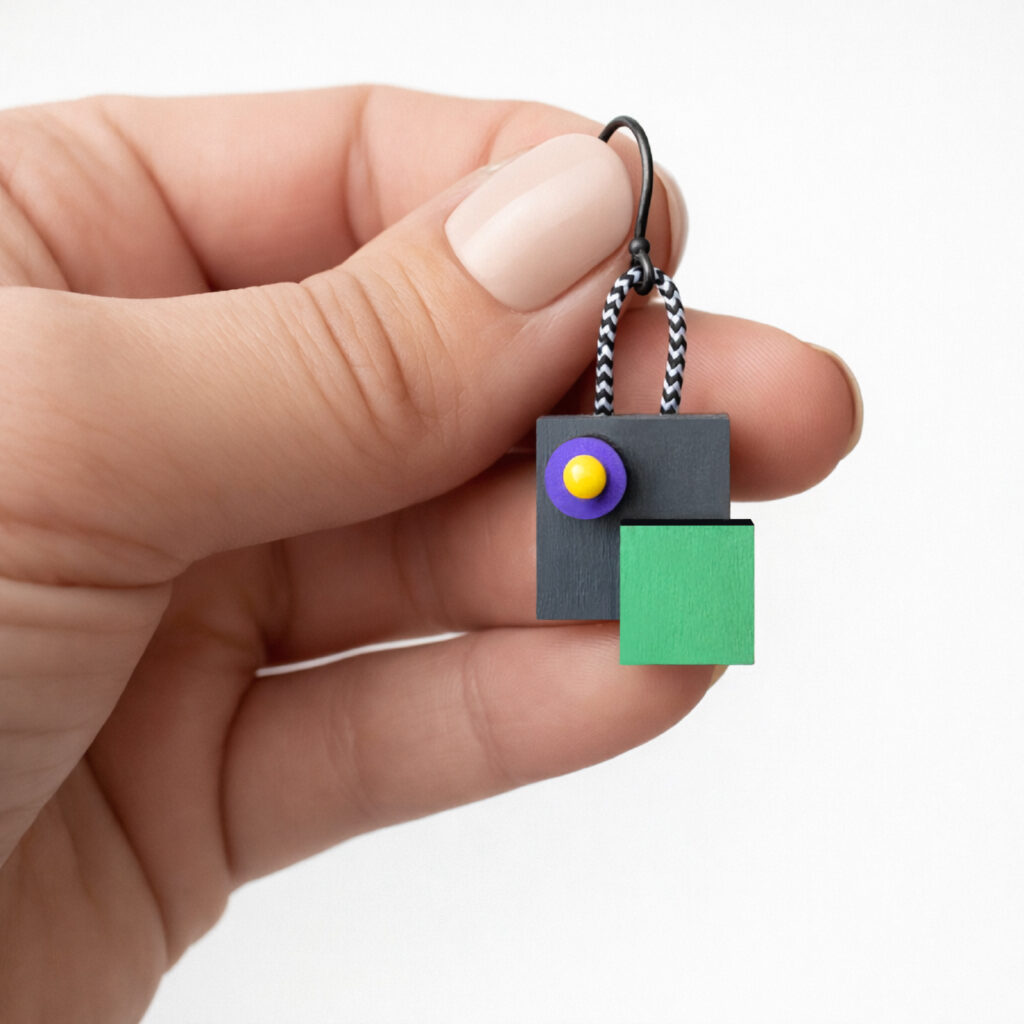 Colorful geometric wooden earring shown in hand for scale