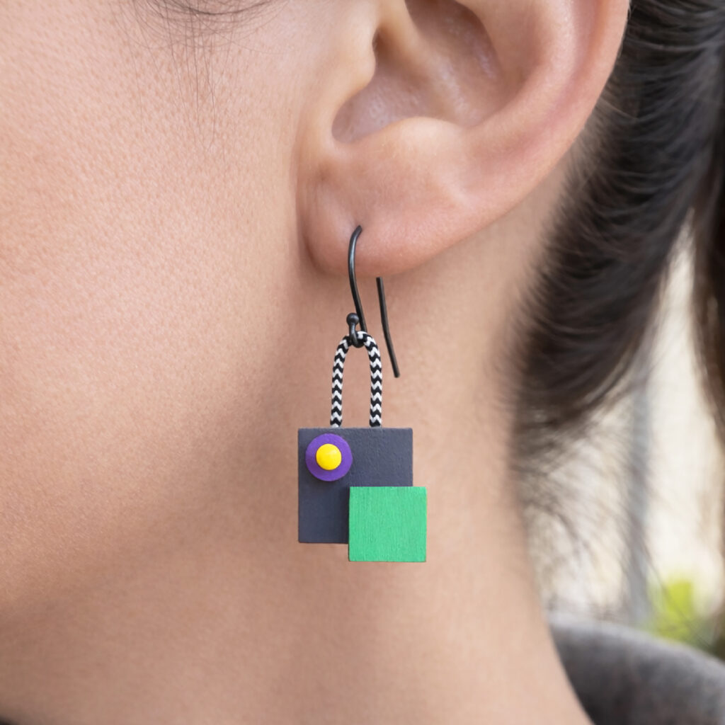 Colorful mismatched geometric wooden dangle earring worn on the ear