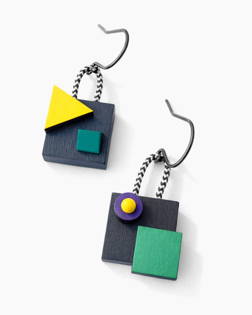 Colorful mismatched geometric wooden dangle earrings with layered shapes on a white background