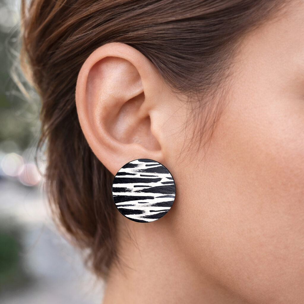 Large black and white abstract wooden disc earrings worn on ear
