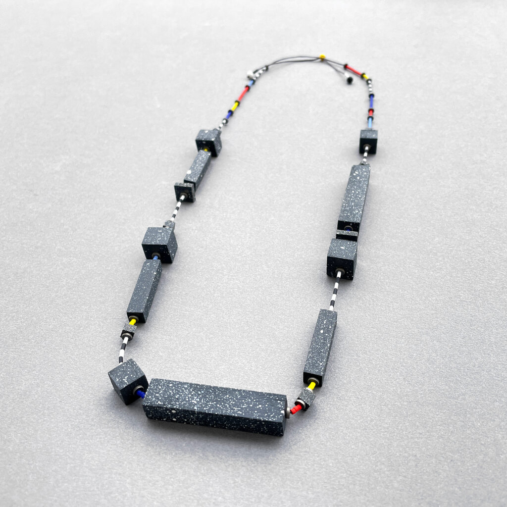 Full view of speckled geometric statement necklace with black-and-white striped and multicolored details