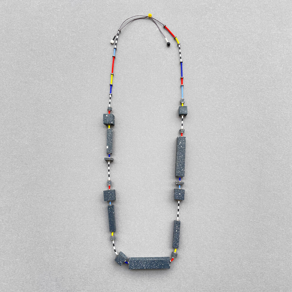Long geometric statement necklace with dark speckled wooden forms and colorful linear accents