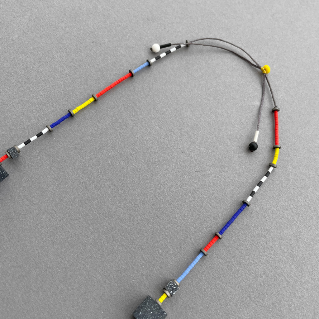Close-up of multicolored cord and striped details on the geometric statement necklace