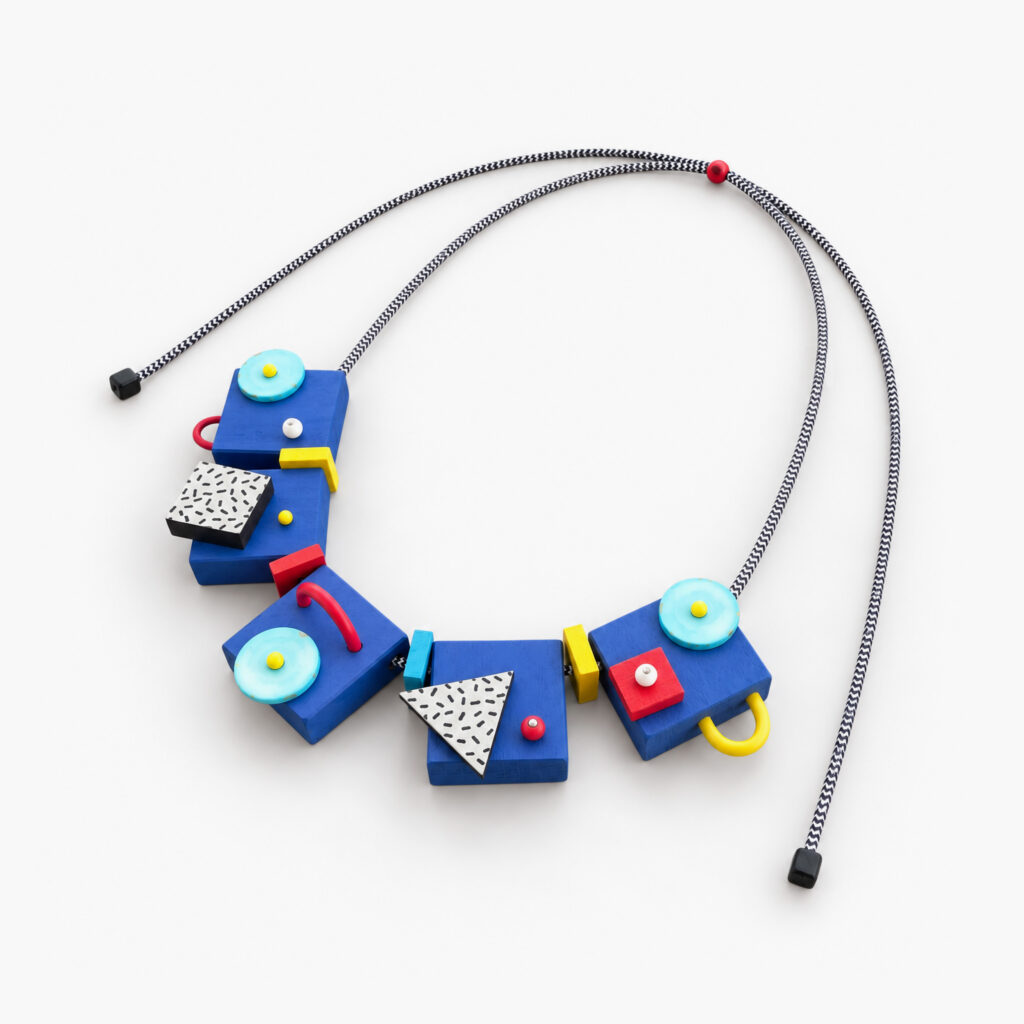 Blue geometric wooden statement necklace with turquoise, red, yellow and black-and-white details on a white background