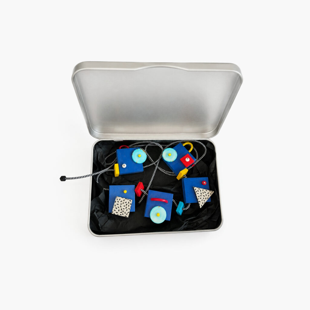 Blue geometric wooden statement necklace presented in a metal gift box