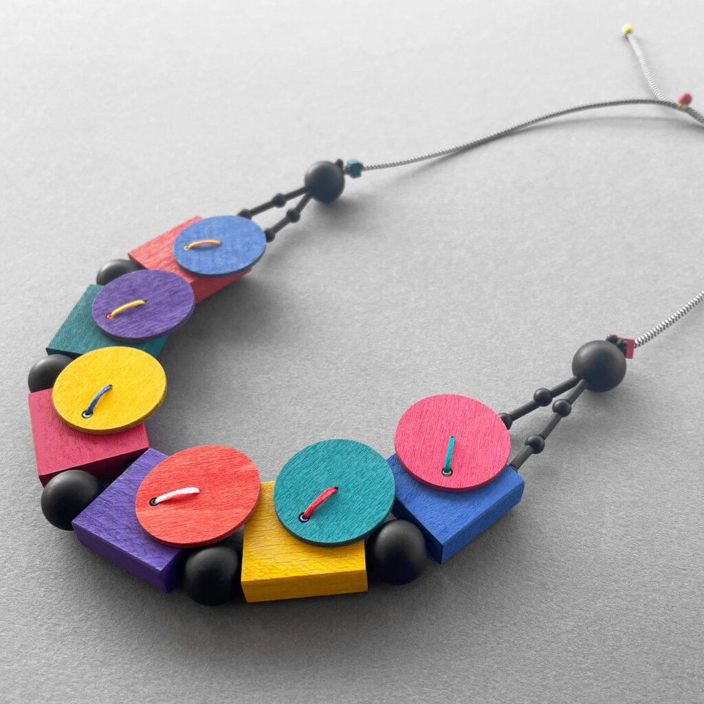 Playful multicolor geometric statement necklace on grey background