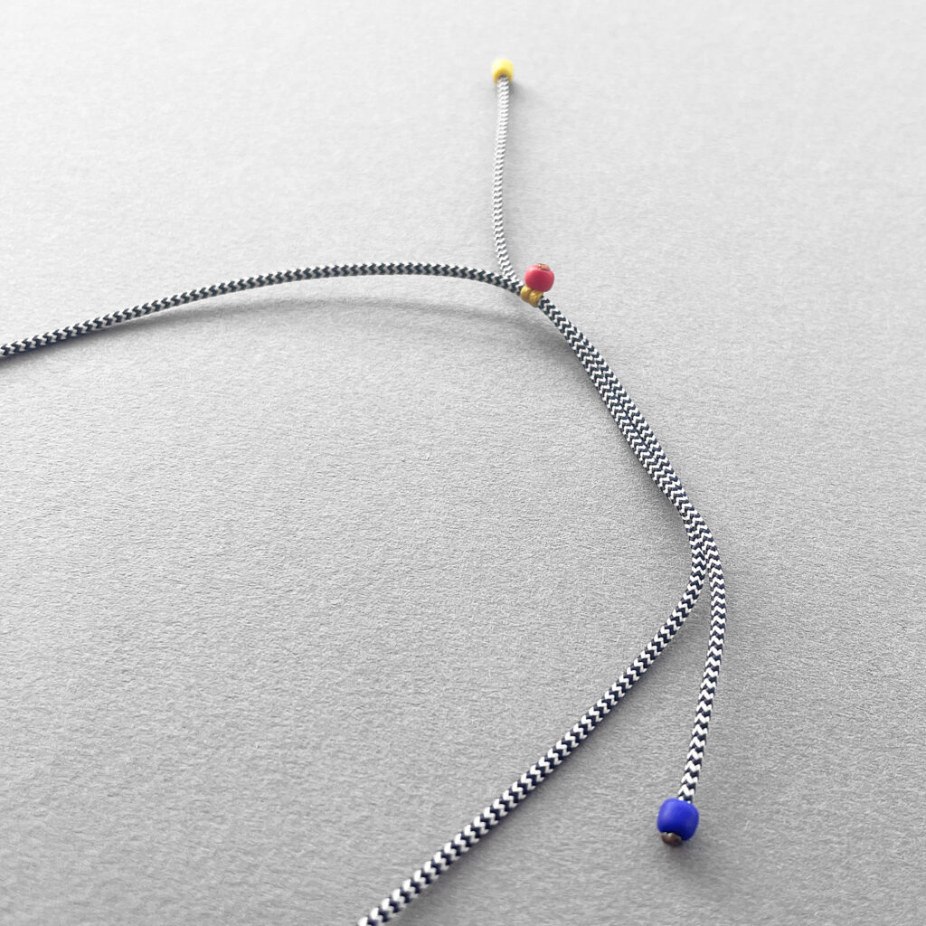 Adjustable grey cord and sliding bead closure of geometric necklace