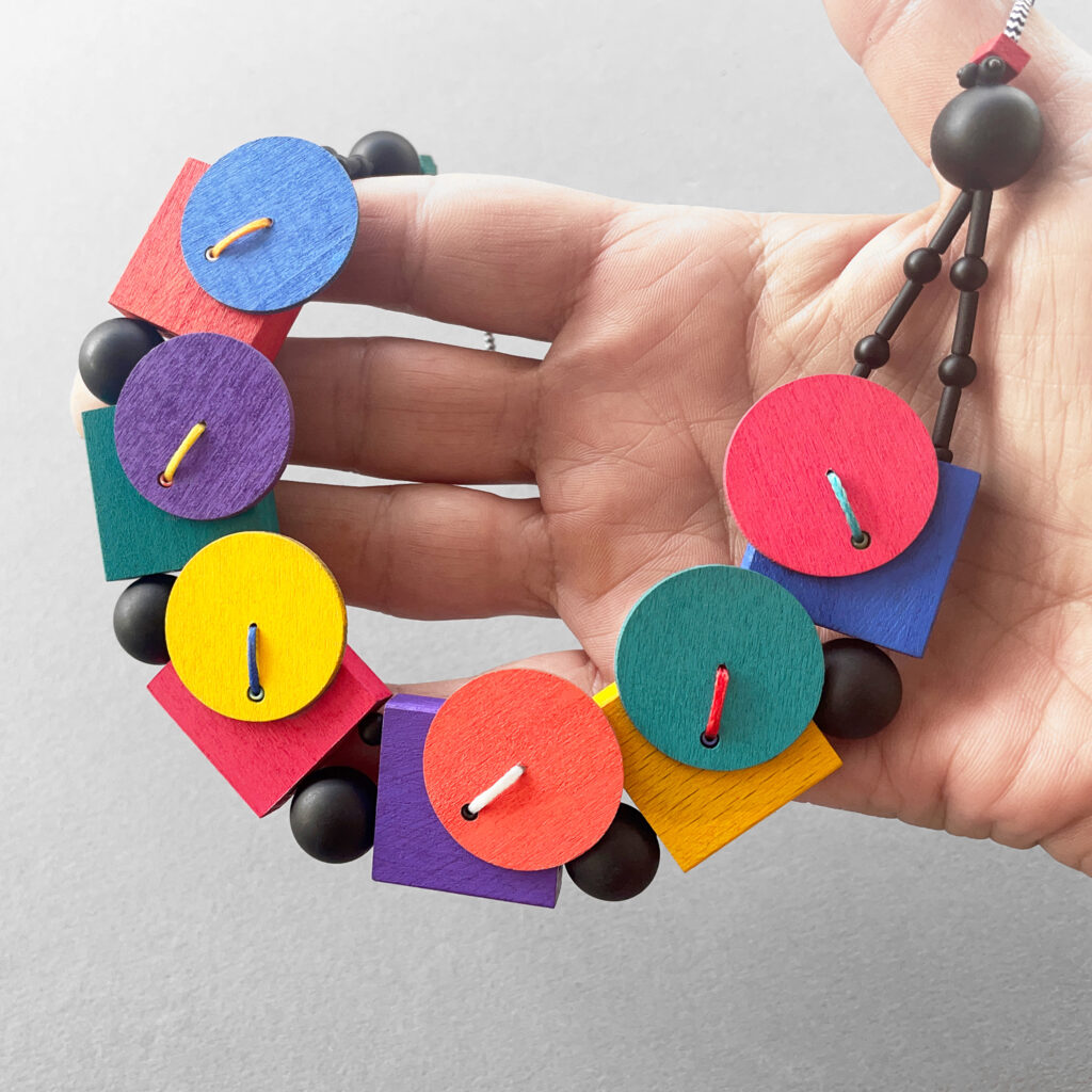 Colorful geometric statement necklace shown in hand