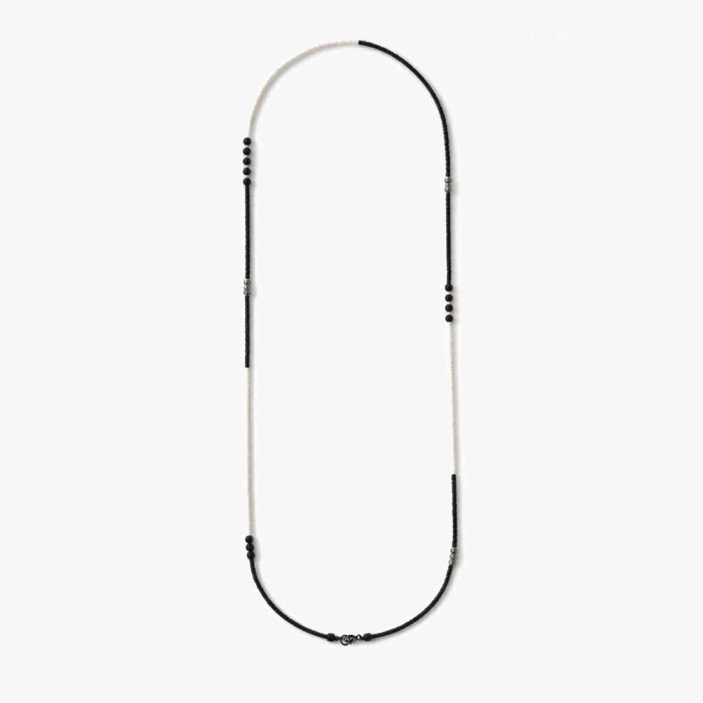 Long black and white minimalist beaded necklace on white background