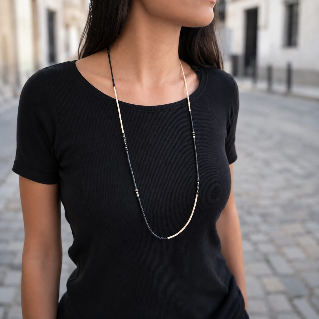 Long black and white beaded necklace worn with black top
