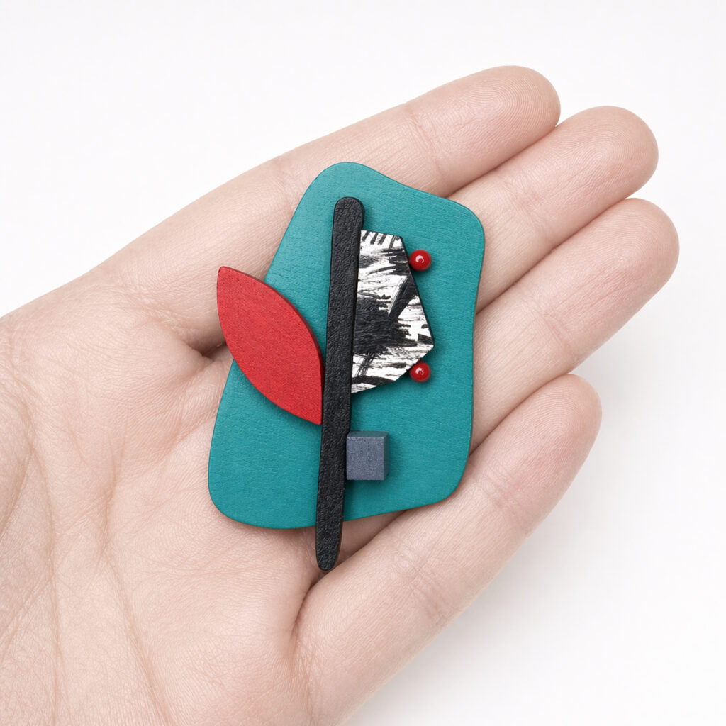 Petrol red and black abstract brooch shown in hand