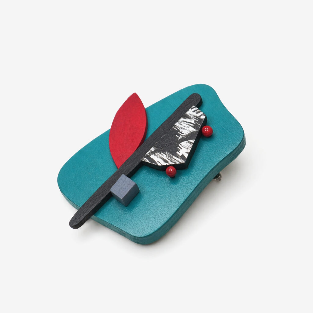 Petrol red and black geometric statement brooch on white background