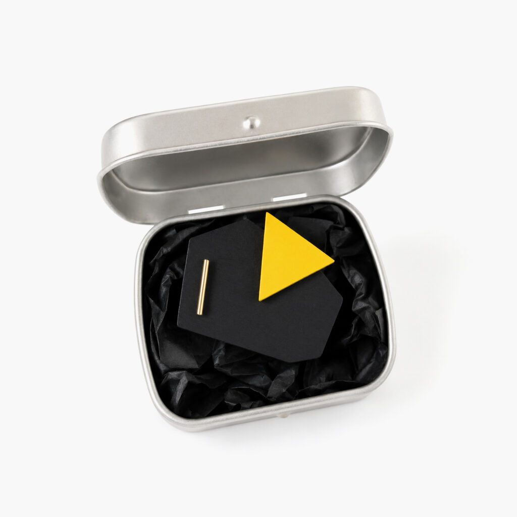 Black and yellow geometric wooden brooch presented in a metal gift box